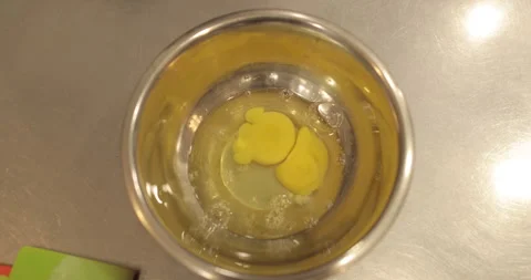 Raw chicken eggs are broken into a metal bowl on the table Stock Footage 256983540