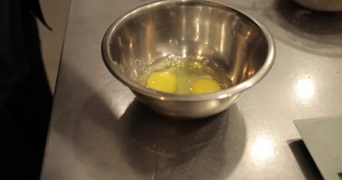 Raw chicken eggs are broken into a metal bowl on the table Stock Footage 256983548