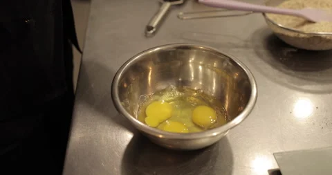 Raw chicken eggs are broken into a metal bowl on the table Stock Footage 256983872