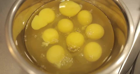Raw chicken eggs are broken into a metal bowl on the table Stock Footage 256984052