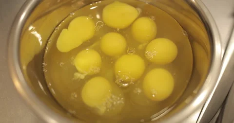 Raw chicken eggs are broken into a metal bowl on the table Stock Footage 256984174