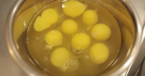 Raw chicken eggs are broken into a metal bowl on the table Stock Footage 256984229