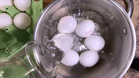 Raw chicken eggs are poured with water in a metal pan for further cooking. Top v Stock Footage 300459677