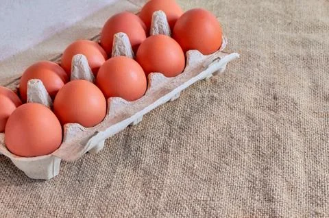 Raw chicken eggs in a cardboard box on a linen napkin . The view from the top Stock Photos