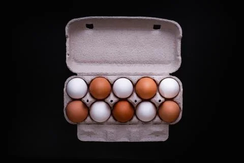 Raw chicken eggs in a package on a black background. Copy space. Space for te Photos