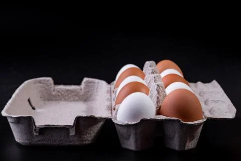 Raw chicken eggs in a package on a black background. Copy space. Space for te Stock Photos
