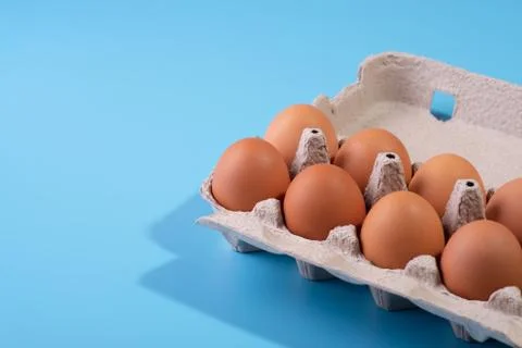 Raw chicken eggs in a package on a blue background. Copy space. Space for tex Photos