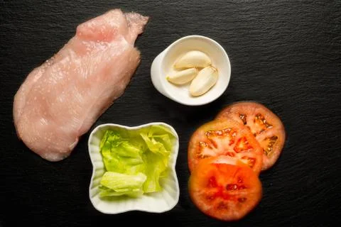 Raw chicken fillet with tomatoes, lettuce, garlic and salt . Food background, Photos