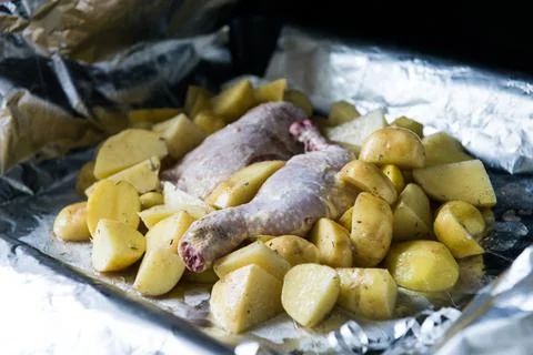 Raw chicken leg with potatoes ready to be cooked. Raw chicken with raw potato Stock Photos