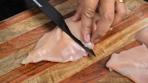 Raw Chicken meat cutting with knife on board in kitchen room Stock Photos