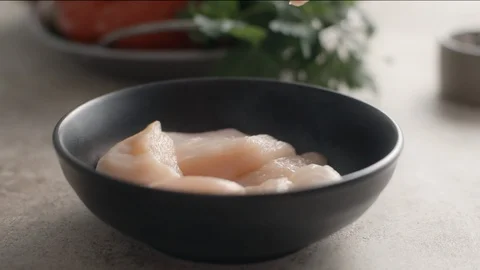 Raw chicken pieces falls down in slow motion to the bowl, cooking the chicken Video stock 128047324