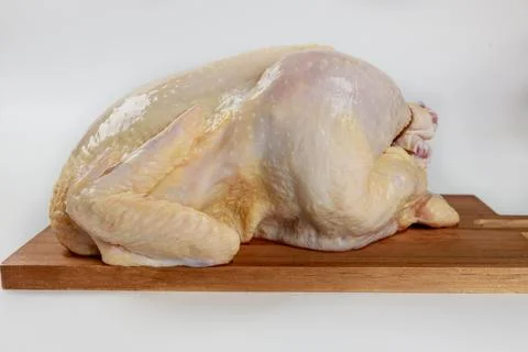 Raw chicken is placed on a cutting board and prepared for cooking. Stock Photos