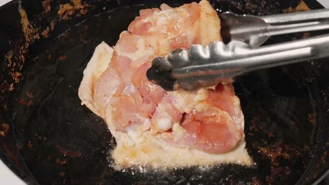 Raw chicken placed in hot cast iron pan slow motion Stock Footage 164007388