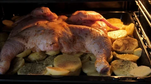 Raw chicken with spices with potatoes on a baking sheet in the oven Stock Footage 128667773