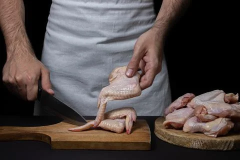 Raw chicken wings on a black background. The chef prepares chicken wings on a da Stock Photos