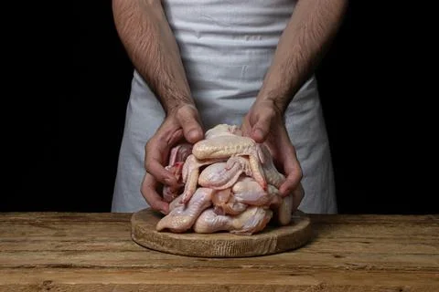 Raw chicken wings on a black background. The chef prepares chicken wings on a da Stock Photos