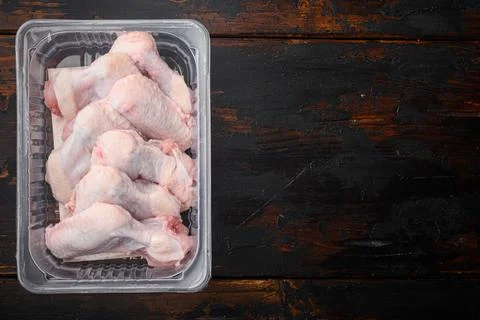 Raw chicken wings in plastic pack, on old dark wooden table background, top v Stock Photos