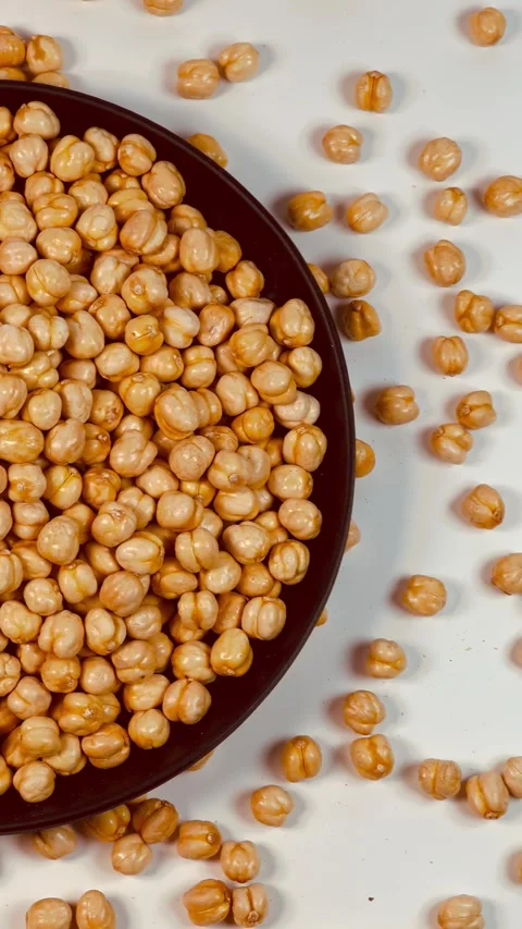 Raw chickpeas in dark plate, white background, vertical format, top view Stock Footage 336471545