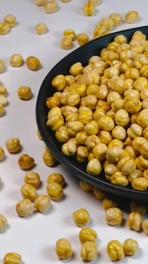 Raw chickpeas in dark plate, white background, vertical format, angled view Stock Footage 336471550