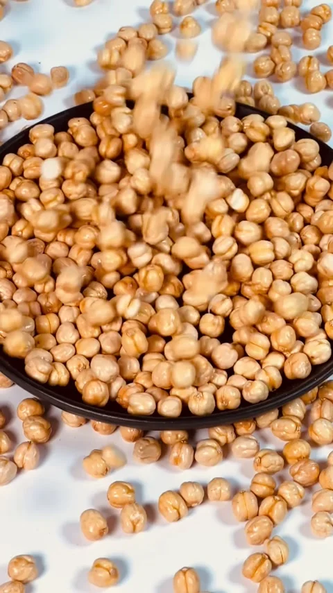 Raw chickpeas falling in dark plate, white background , slow motion top view Stock Footage 336471548