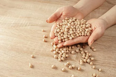 Raw chickpeas in hands Stock Photos