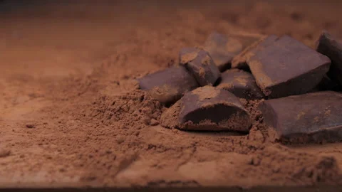 Raw chocolate falling into cacoa powder 4k Stock Footage 148312633