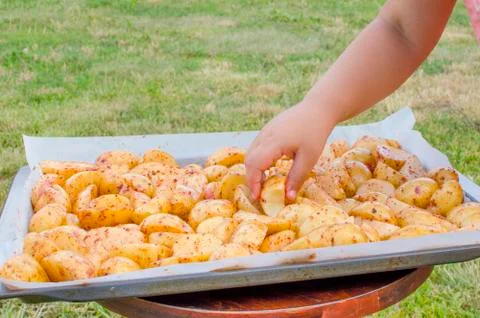Raw chopped potatoes on a baking sheet. Hand girls Foto stock