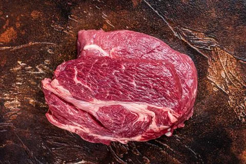 Raw Chuck eye roll beef steak on butcher table. Dark background. Top view Stock Photos