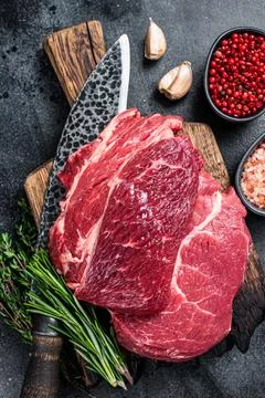 Raw Chuck eye roll Black Angus prime beef steak on butcher board with knife Stock Photos
