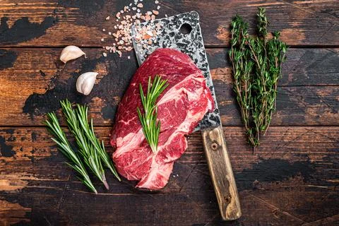 Raw Chuck eye roll Black Angus prime beef steak on butcher cleaver. Dark wooden Stock Photos