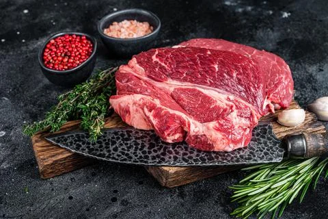 Raw Chuck eye roll Black Angus prime beef steak on butcher board with knife Stock Photos