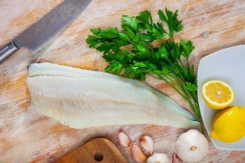 Raw cod fillet with garlic and lemon on wooden surface Stock Photos