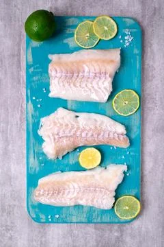 Raw cod fillet on turquoise board Stock Photos