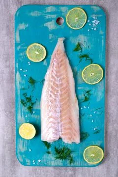 Raw cod fillet on turquoise colored wooden board Foto stock