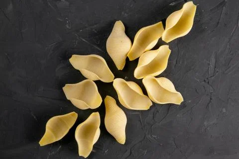 Raw conchiglie or seashell shaped pasta isolated on black background Foto stock