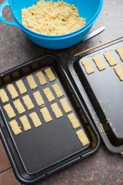 Raw cookie dough being cut and packed onto baking tray Stock Photos