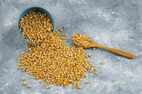 Raw corn kernels out of bowl on marble surface Stock Photos