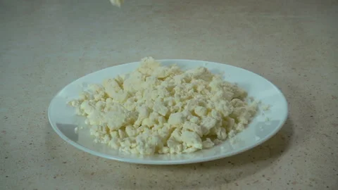 Raw cottage cheese falls in slow motion into a plate Stock Footage 130491920