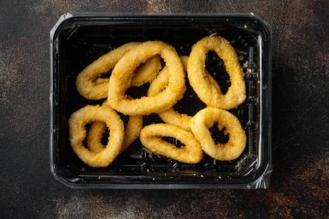Raw Crispy deep fried onion or Calamari ring plastic pack, on old dark rustic Stock Photos