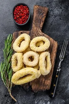 Raw crispy squid rings in breadcrumbs on a cutting board. Black background. Top Stock Photos