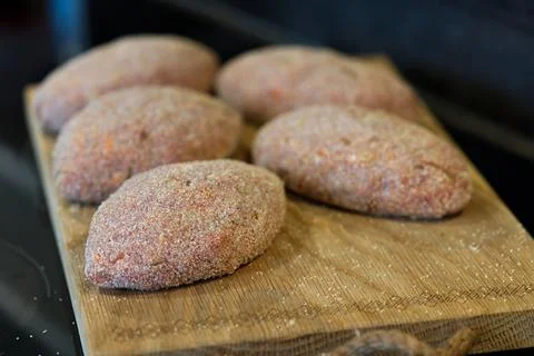 Raw cutlets made of ground beef meat on a wooden chopping board. Stock Photos