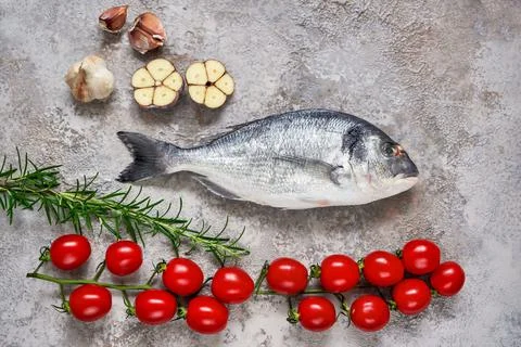 Raw dorado fish with vegetables on rustic background. Sea bream or dorada fish Stock Photos