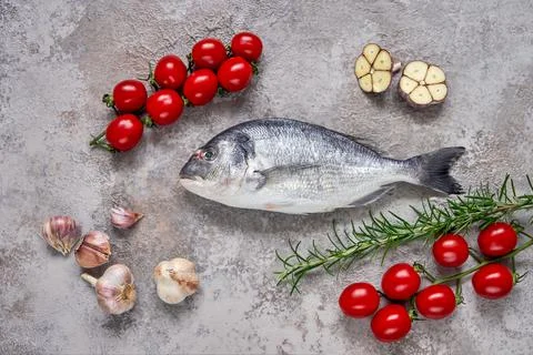 Raw dorado fish with vegetables on the table. Sea bream or dorada fish. Top view Foto stock