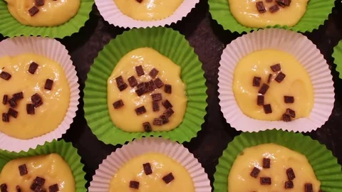 Raw dough for muffins in special paper baking dish sprinkled with chocolate Stock Footage