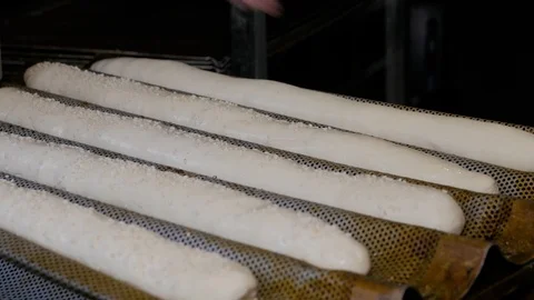 Raw dough on oven tray. Hand sprinkles baguettes with sesame seeds. Stock Footage 108634026