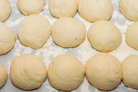 Raw dough rolled into balls is on the table rolled in flour Stock Photos