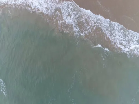 Raw drone lookdown shot of waves approaching the shore 스톡 동영상 75805855