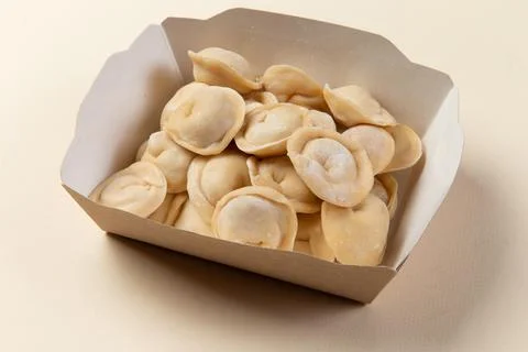 Raw dumplings in a package. On a light background. Stock Photos