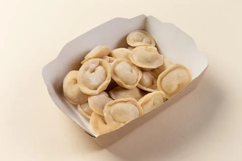 Raw dumplings in a package. On a light background. Stock Photos