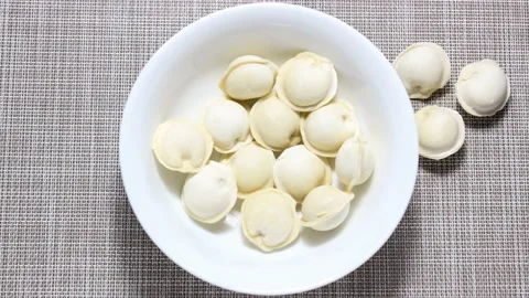 Raw dumplings take turns jumping into a white plate. Stock Footage 152139846